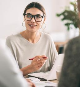 A female reinsurance broker talks to two clients at a desk
